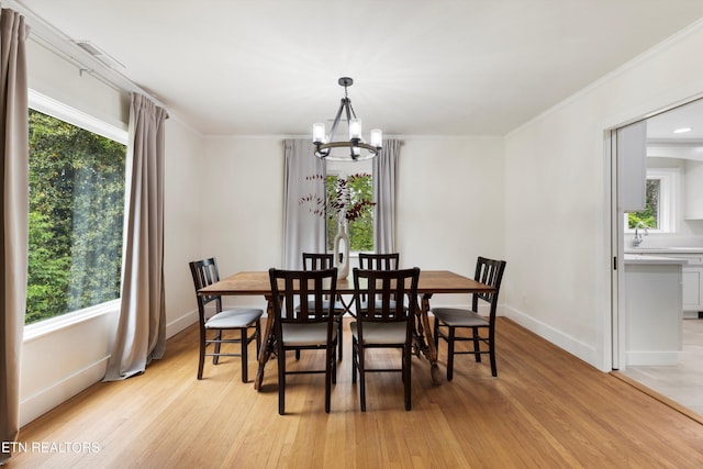 dining room featuring an inviting chandelier, ornamental molding, a healthy amount of sunlight, and light wood-type flooring