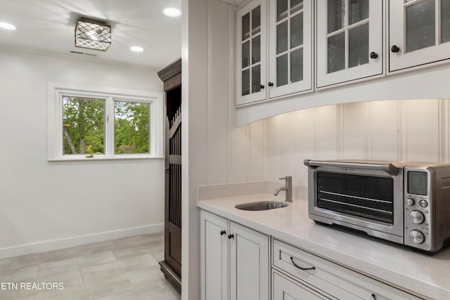 kitchen with light stone countertops, sink, and white cabinets