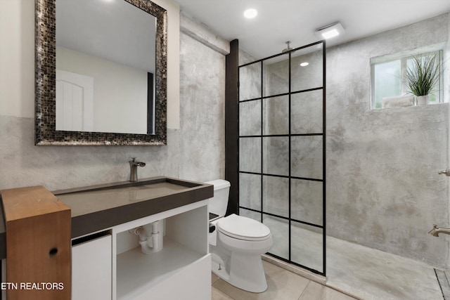 bathroom with vanity, tile patterned flooring, toilet, and tiled shower