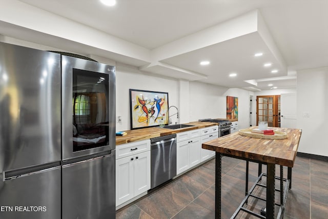 kitchen with white cabinetry, appliances with stainless steel finishes, sink, and butcher block countertops