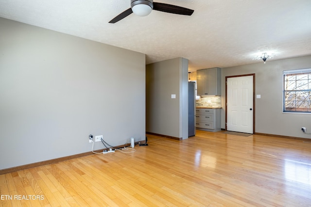 unfurnished living room with a textured ceiling, light hardwood / wood-style flooring, and ceiling fan