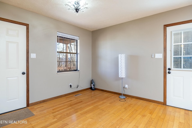 foyer entrance featuring a textured ceiling and light wood-type flooring