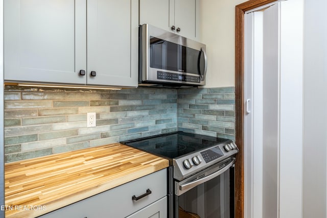 kitchen featuring appliances with stainless steel finishes, backsplash, and butcher block countertops