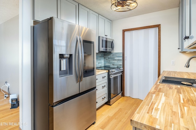 kitchen featuring appliances with stainless steel finishes, sink, wood counters, and decorative backsplash