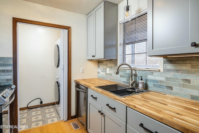 kitchen featuring wood counters, sink, stainless steel range with electric cooktop, dishwasher, and pendant lighting