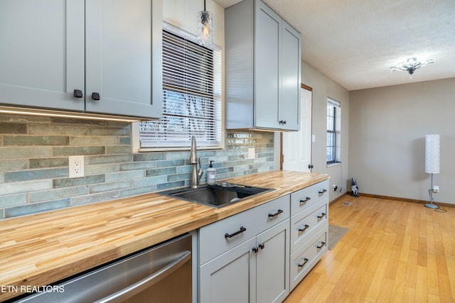 kitchen featuring sink, gray cabinets, butcher block counters, decorative backsplash, and stainless steel dishwasher