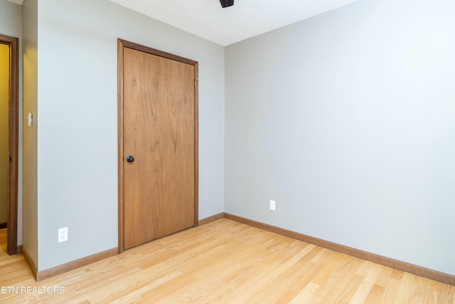 unfurnished bedroom with ceiling fan, a closet, and light wood-type flooring