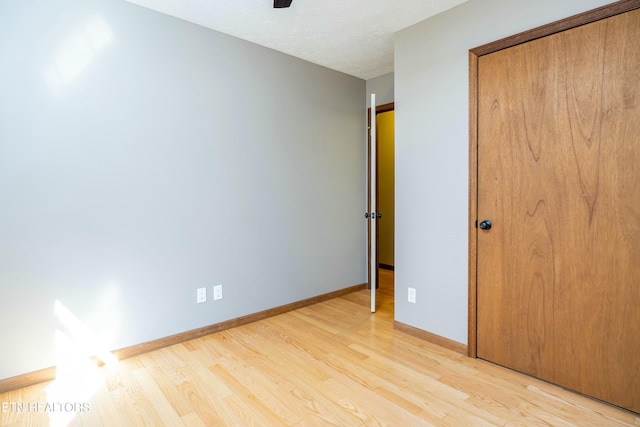 unfurnished bedroom with ceiling fan, light hardwood / wood-style floors, a closet, and a textured ceiling