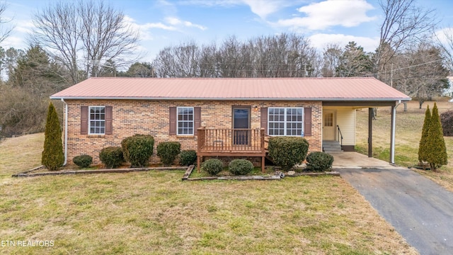 ranch-style home featuring metal roof, driveway, brick siding, and a front yard