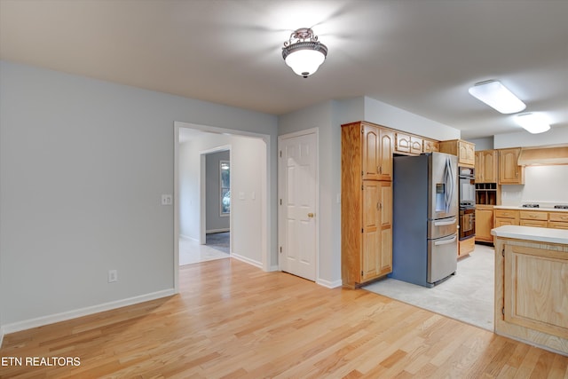 kitchen featuring stainless steel appliances, light brown cabinetry, and light wood-type flooring