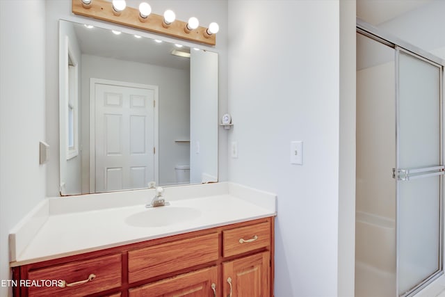 bathroom with vanity, toilet, and a shower with door