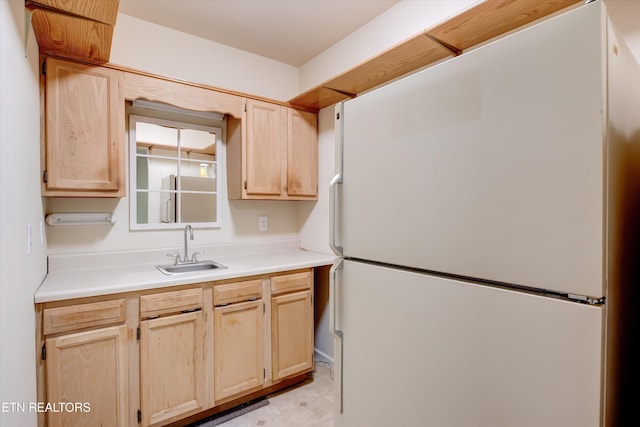 kitchen featuring white refrigerator, sink, and light brown cabinetry