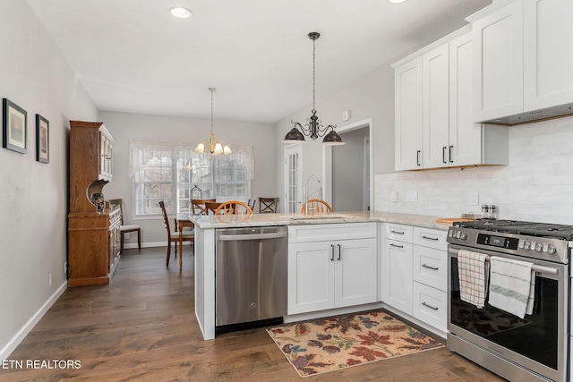 kitchen with decorative light fixtures, white cabinetry, sink, kitchen peninsula, and stainless steel appliances