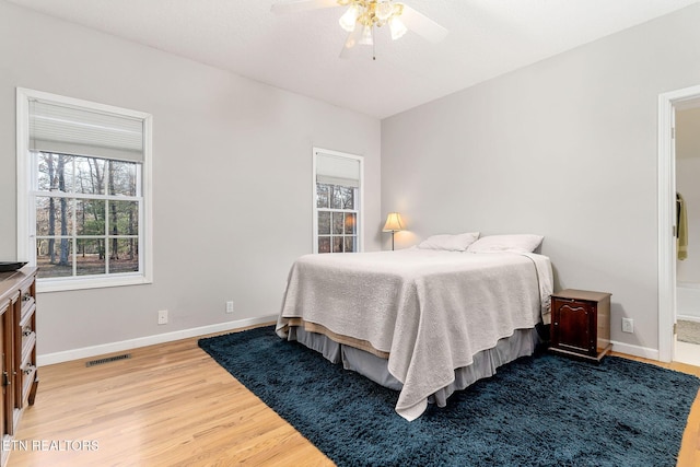 bedroom featuring wood-type flooring, ensuite bathroom, and ceiling fan