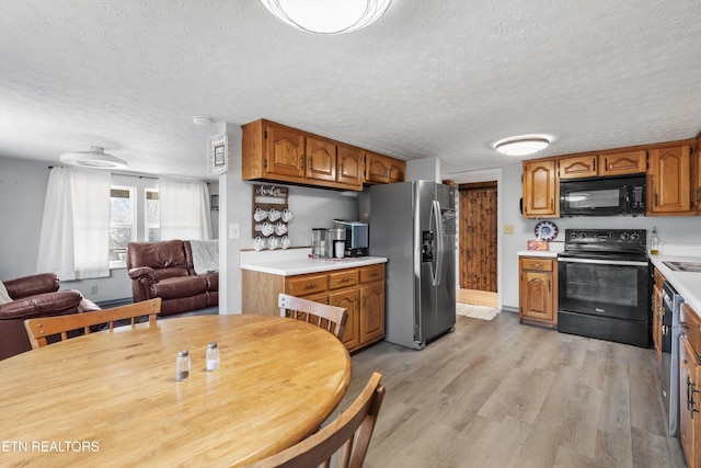 kitchen with a textured ceiling, light hardwood / wood-style flooring, and black appliances