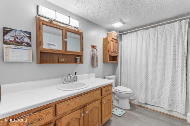 bathroom featuring hardwood / wood-style flooring, vanity, walk in shower, toilet, and a textured ceiling