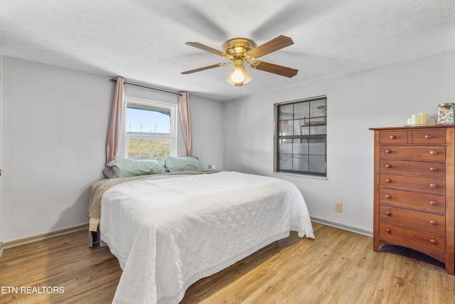 bedroom featuring ceiling fan, light hardwood / wood-style floors, and a textured ceiling