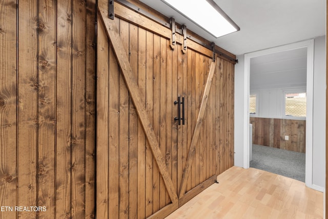 interior space with hardwood / wood-style flooring, wooden walls, and a barn door