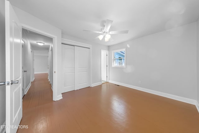 unfurnished bedroom with wood-type flooring, a closet, and ceiling fan