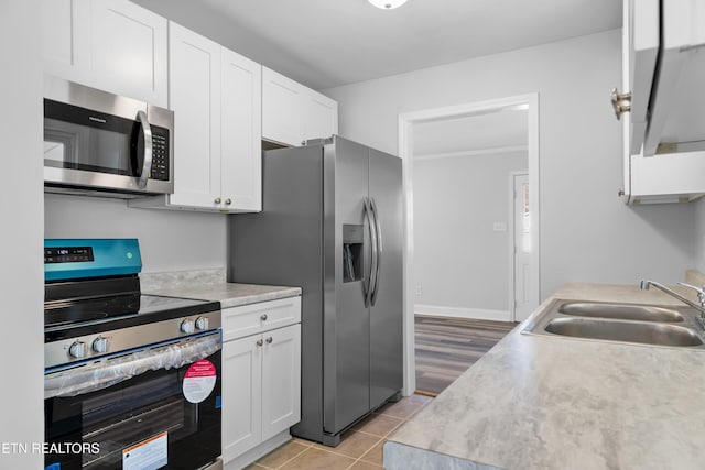 kitchen featuring white cabinetry, sink, light tile patterned flooring, and appliances with stainless steel finishes