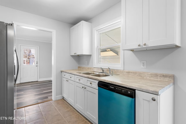 kitchen featuring appliances with stainless steel finishes, sink, light tile patterned floors, and white cabinets