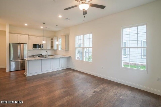 kitchen featuring pendant lighting, appliances with stainless steel finishes, white cabinetry, dark hardwood / wood-style flooring, and kitchen peninsula