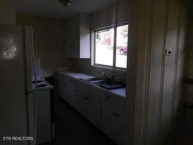 kitchen featuring white refrigerator, sink, and electric stove