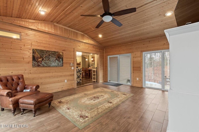 sitting room with lofted ceiling, wooden ceiling, wooden walls, ceiling fan, and hardwood / wood-style floors