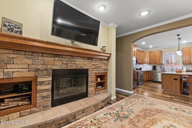 living room with a stone fireplace, ornamental molding, and dark hardwood / wood-style floors