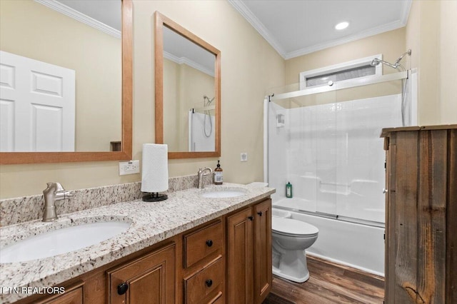 full bathroom featuring hardwood / wood-style floors, shower / bath combination with glass door, ornamental molding, vanity, and toilet