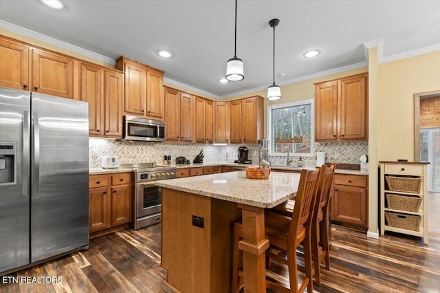 kitchen with dark wood-type flooring, light stone counters, decorative light fixtures, a center island, and appliances with stainless steel finishes