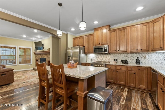 kitchen with pendant lighting, dark wood-type flooring, stainless steel appliances, a center island, and light stone counters