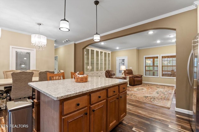 kitchen featuring pendant lighting, crown molding, dark wood-type flooring, stainless steel refrigerator, and a center island