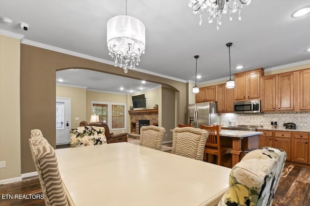 dining area featuring dark hardwood / wood-style flooring, a notable chandelier, a fireplace, and ornamental molding