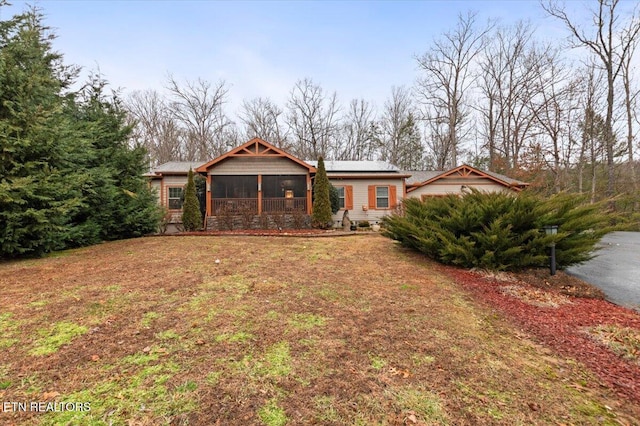 view of front of house with a sunroom, a front yard, and solar panels