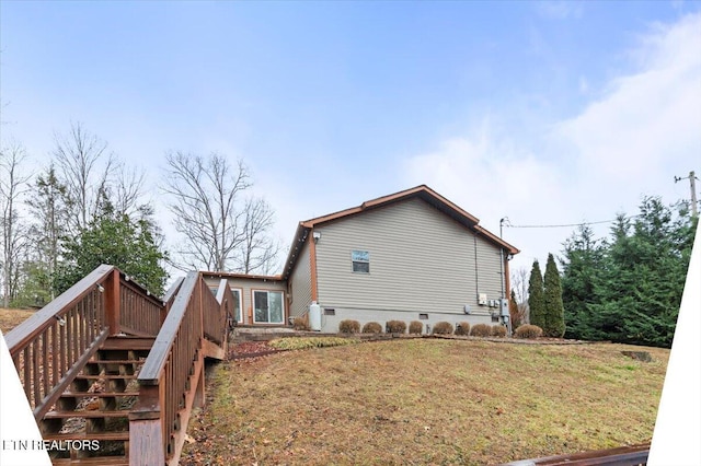 view of home's exterior with a wooden deck and a lawn