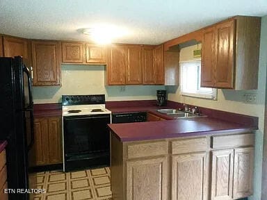 kitchen featuring dishwasher, range with electric cooktop, black fridge, and sink