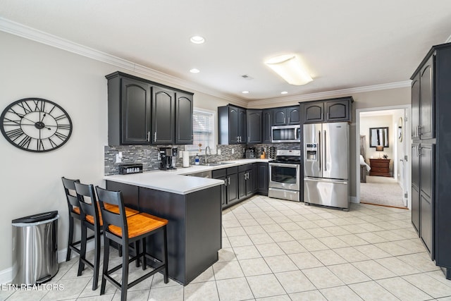 kitchen featuring a peninsula, a sink, ornamental molding, decorative backsplash, and stainless steel appliances