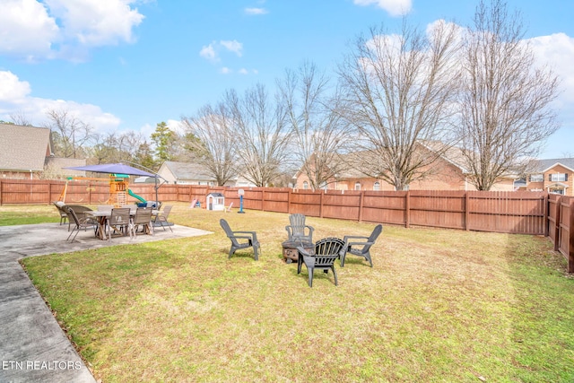 view of yard featuring a patio, an outdoor fire pit, a playground, and a fenced backyard