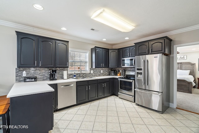 kitchen with backsplash, crown molding, appliances with stainless steel finishes, light tile patterned flooring, and a sink