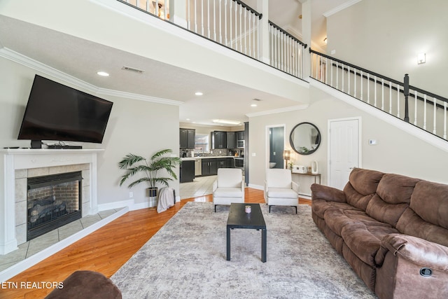 living room with visible vents, crown molding, baseboards, light wood-type flooring, and a fireplace