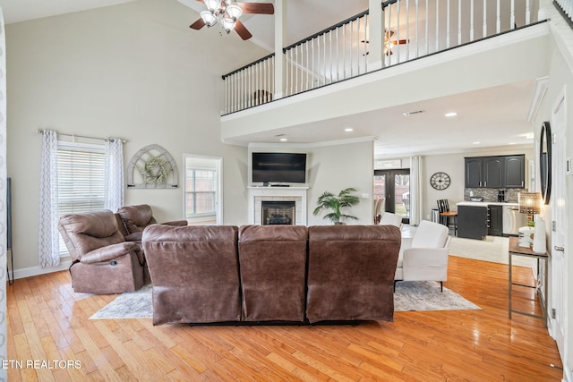 living area featuring a fireplace, a wealth of natural light, a ceiling fan, and light wood finished floors