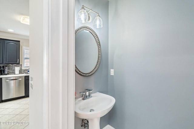 bathroom featuring decorative backsplash, tile patterned floors, ornamental molding, and a sink