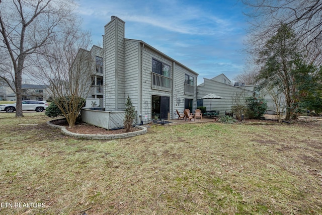 view of side of property with a patio and a lawn