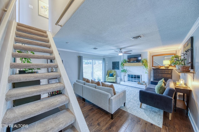 living room with ornamental molding, dark hardwood / wood-style floors, ceiling fan, and a textured ceiling