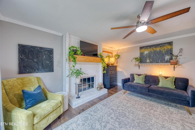 living room with crown molding, a brick fireplace, wood-type flooring, and ceiling fan