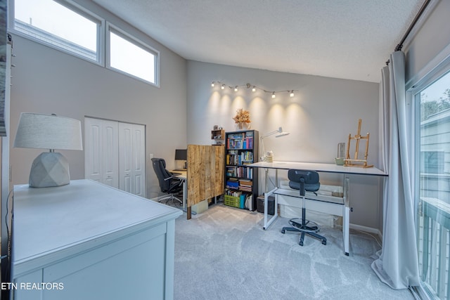 carpeted office space featuring plenty of natural light, vaulted ceiling, and a textured ceiling