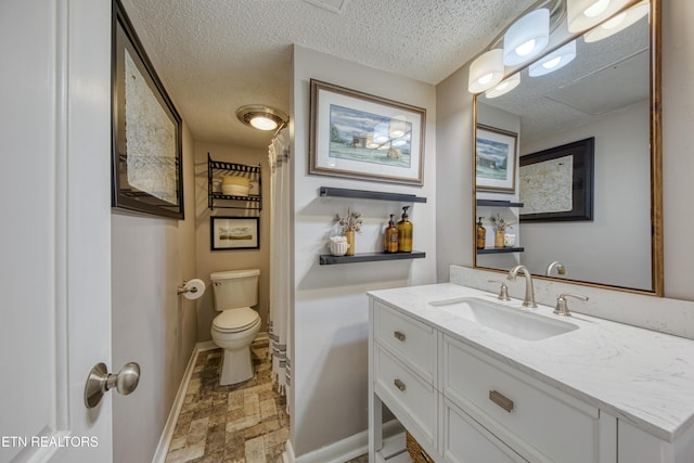 bathroom with vanity, toilet, and a textured ceiling