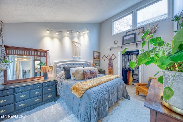 carpeted bedroom featuring a spacious closet, a textured ceiling, and a closet