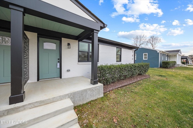 entrance to property with a porch and a yard